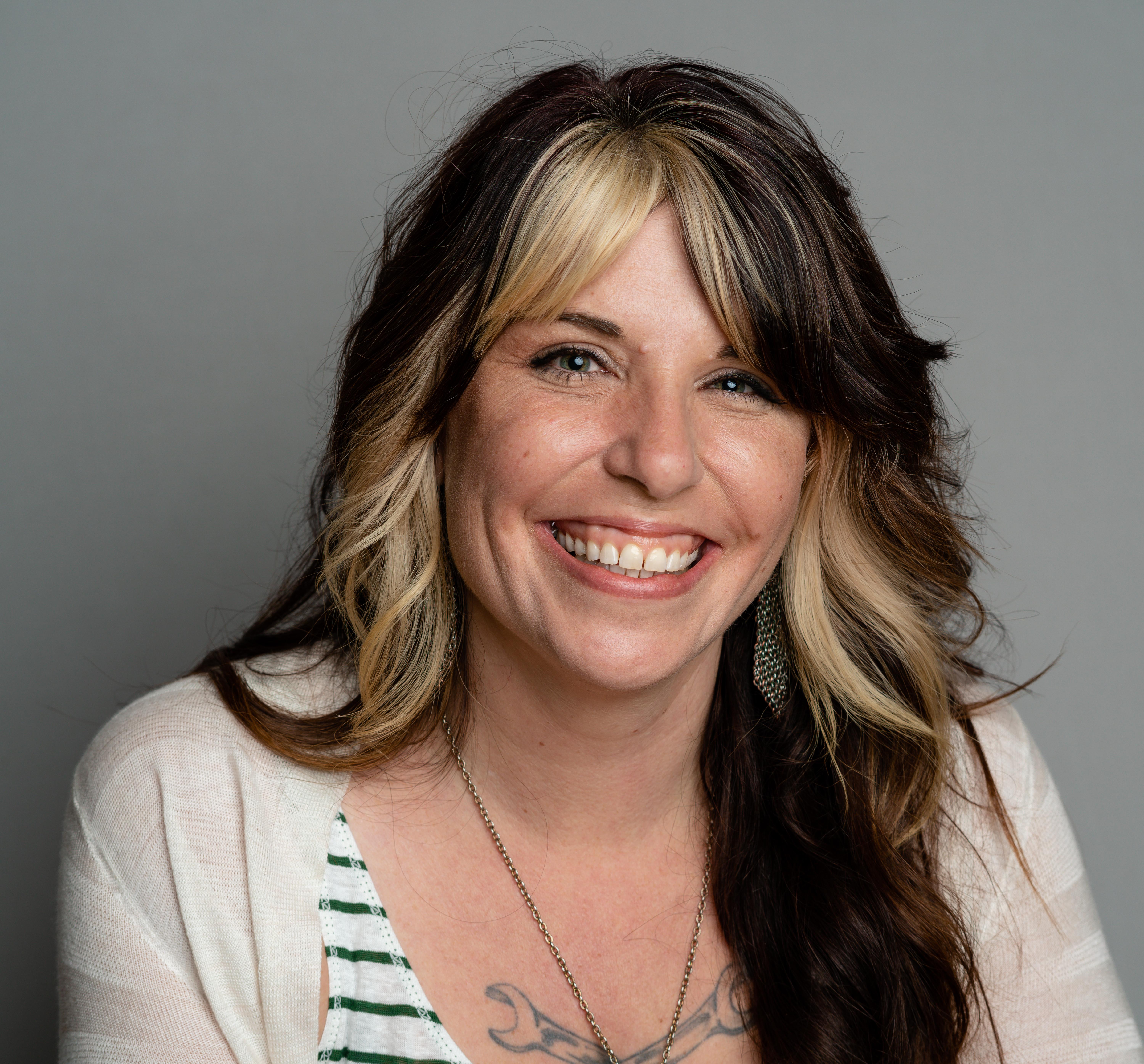 Professional portrait of a woman smiling, wearing white against a grey background.